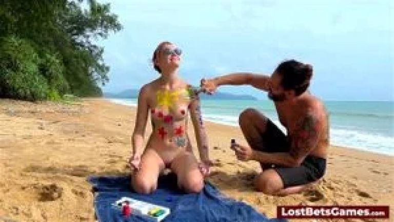 A horny couple playing strip tic tac toe on the beach